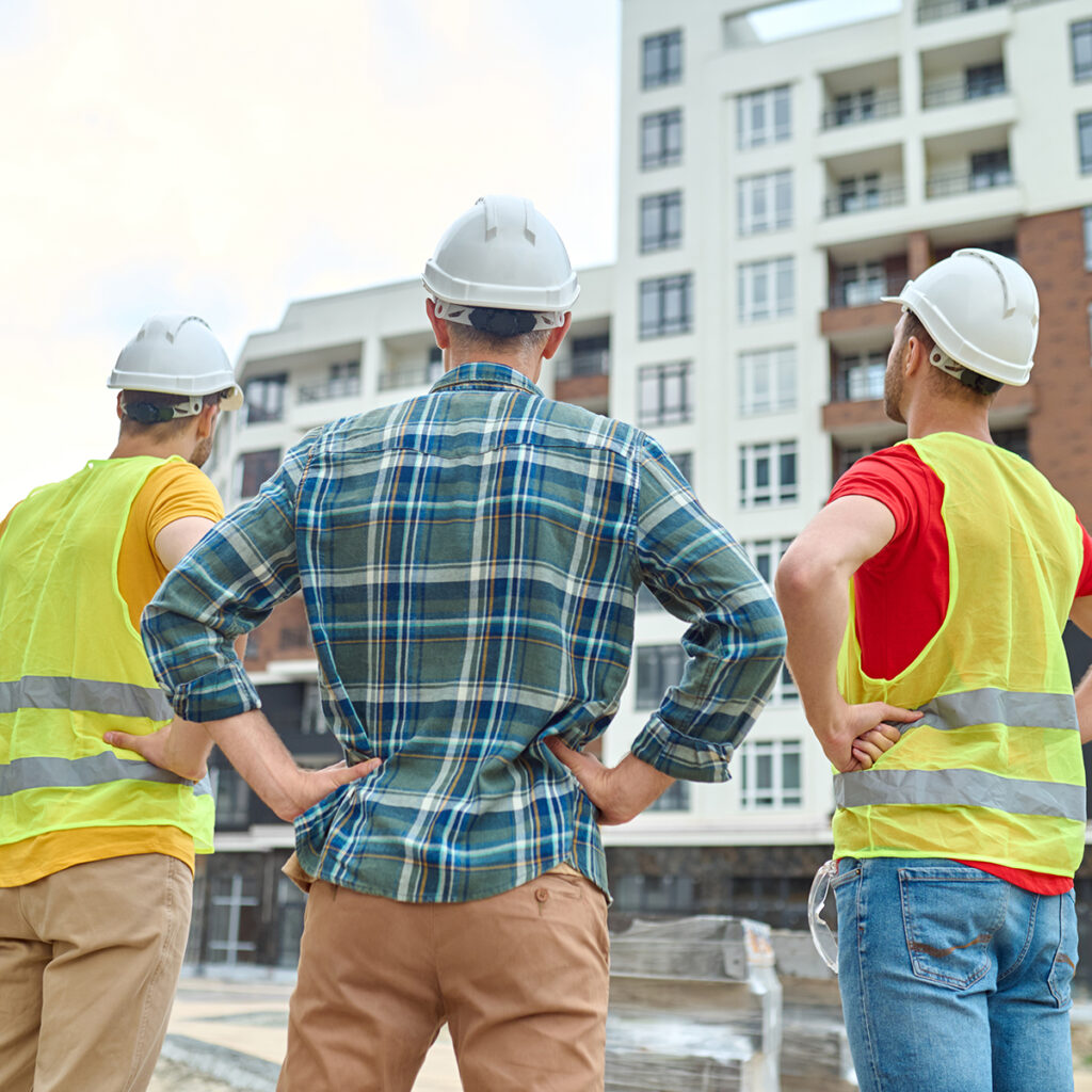 Three construction workers looking over a building.