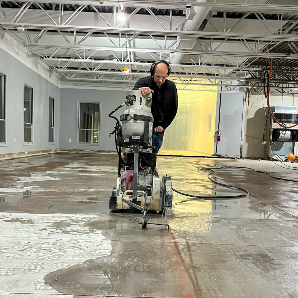 An employee cutting into a concrete floor with a concrete saw.